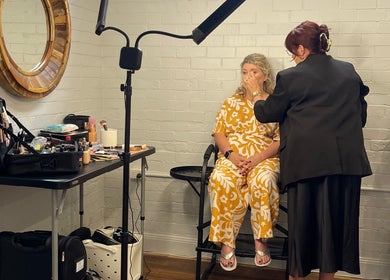 Makeup artist at Colestè Twilley Makeup in Crows Nest, Queensland, AU applies makeup to a seated woman.