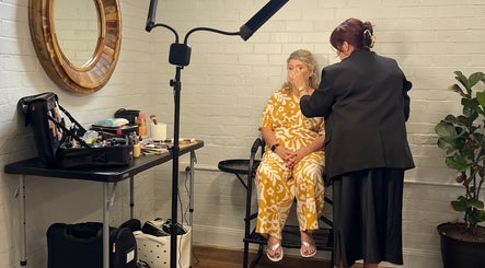 Makeup artist at Colestè Twilley Makeup in Crows Nest, Queensland, AU applies makeup to a seated woman.