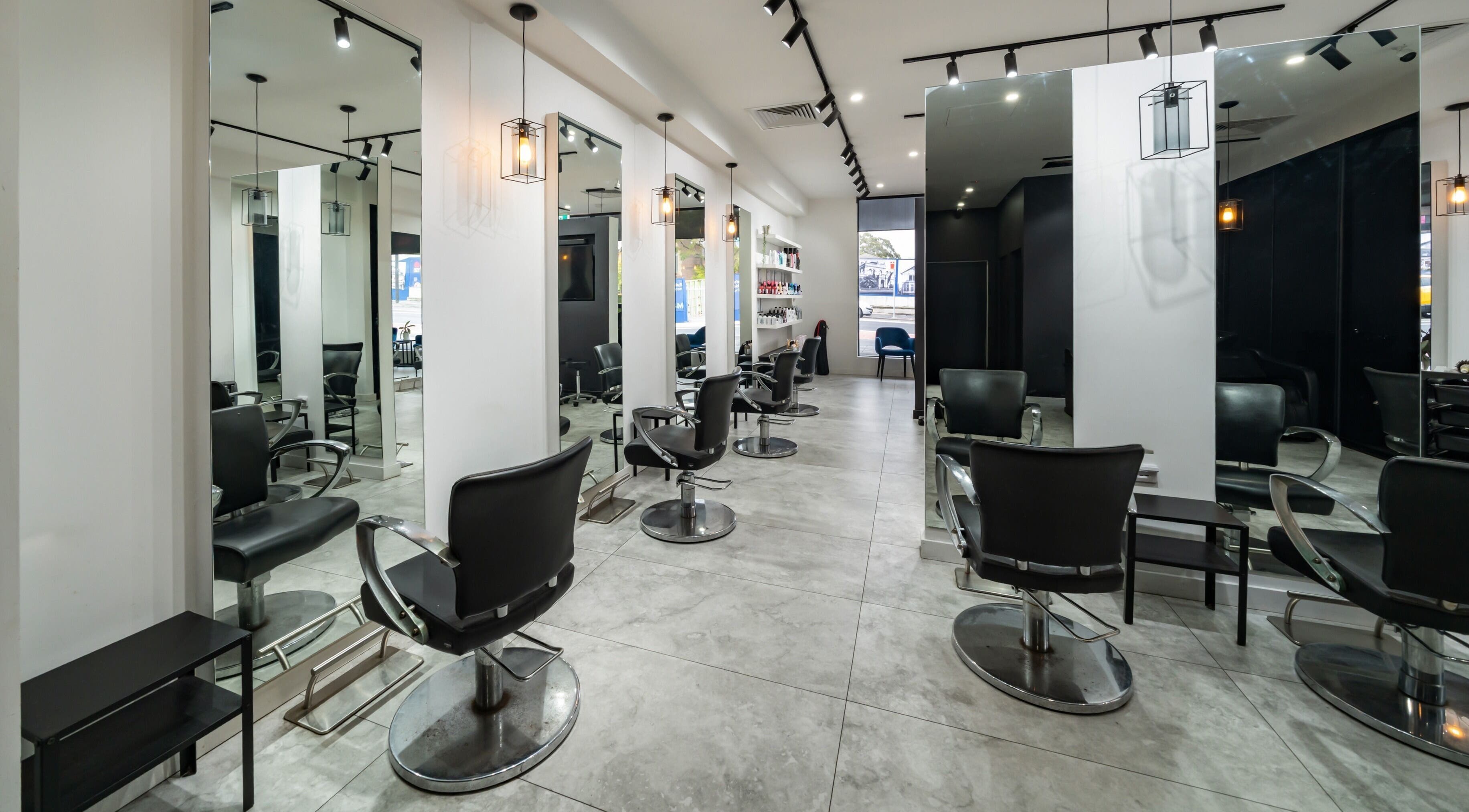 Modern salon interior at Envy Hair and Beauty, Five Dock, New South Wales, AU, featuring sleek black chairs.