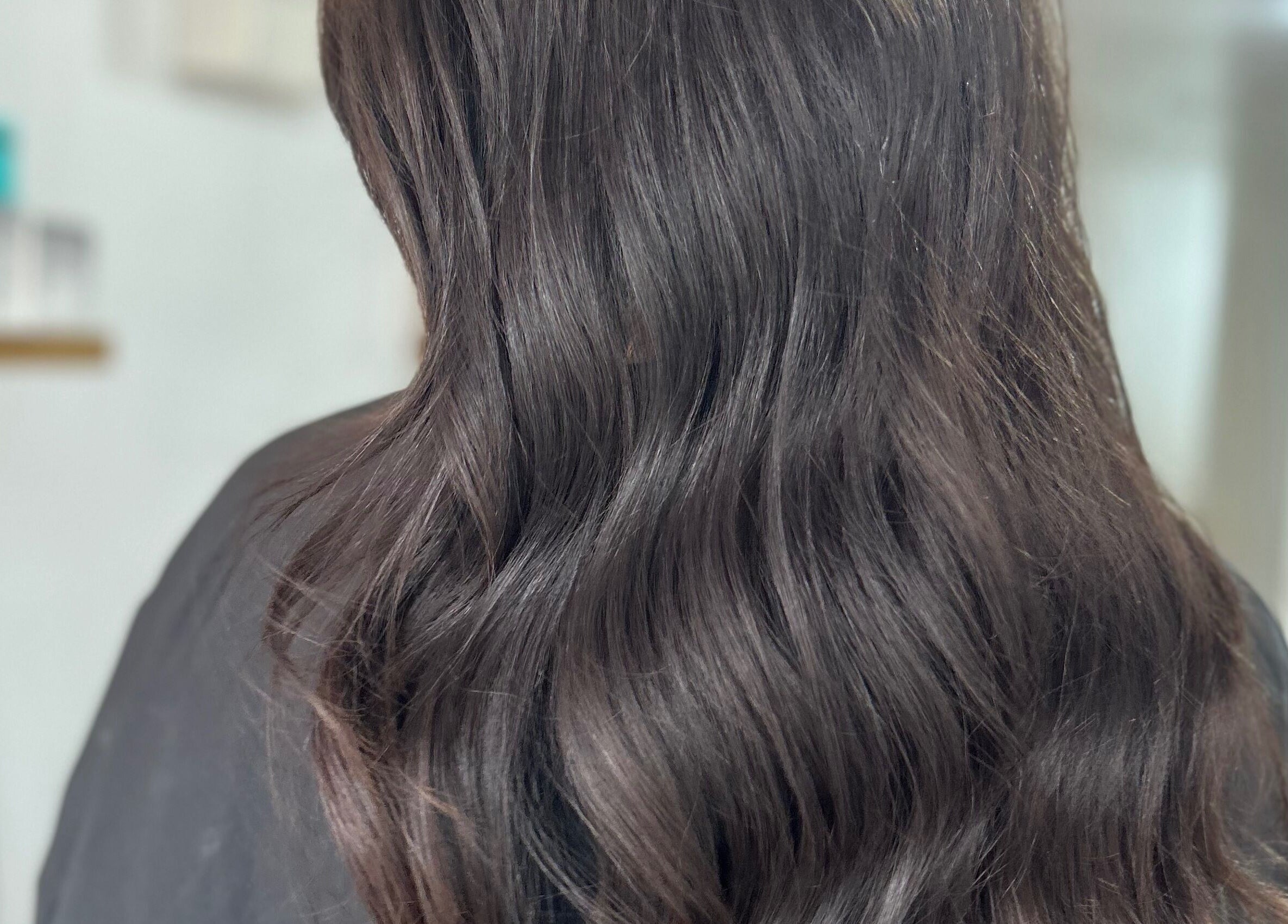 Glossy wavy hairstyle at Navy, Halesworth, England, GB, showcasing sleek, dark hair.