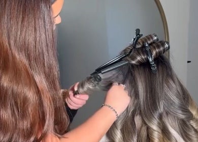 Stylist curling hair at Olivia Tyman Hair Design, Elland, England, GB, showcasing expert hair styling.