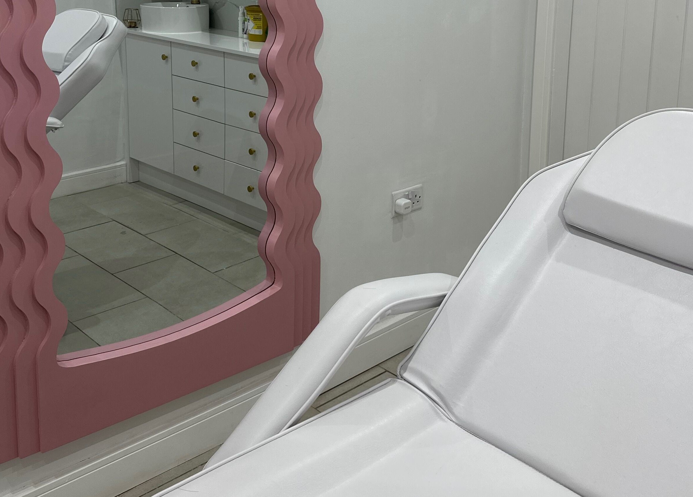 Relaxing treatment room with stylish pink mirror at Clear Touch Medical Aesthetics, Dudley, England, GB.