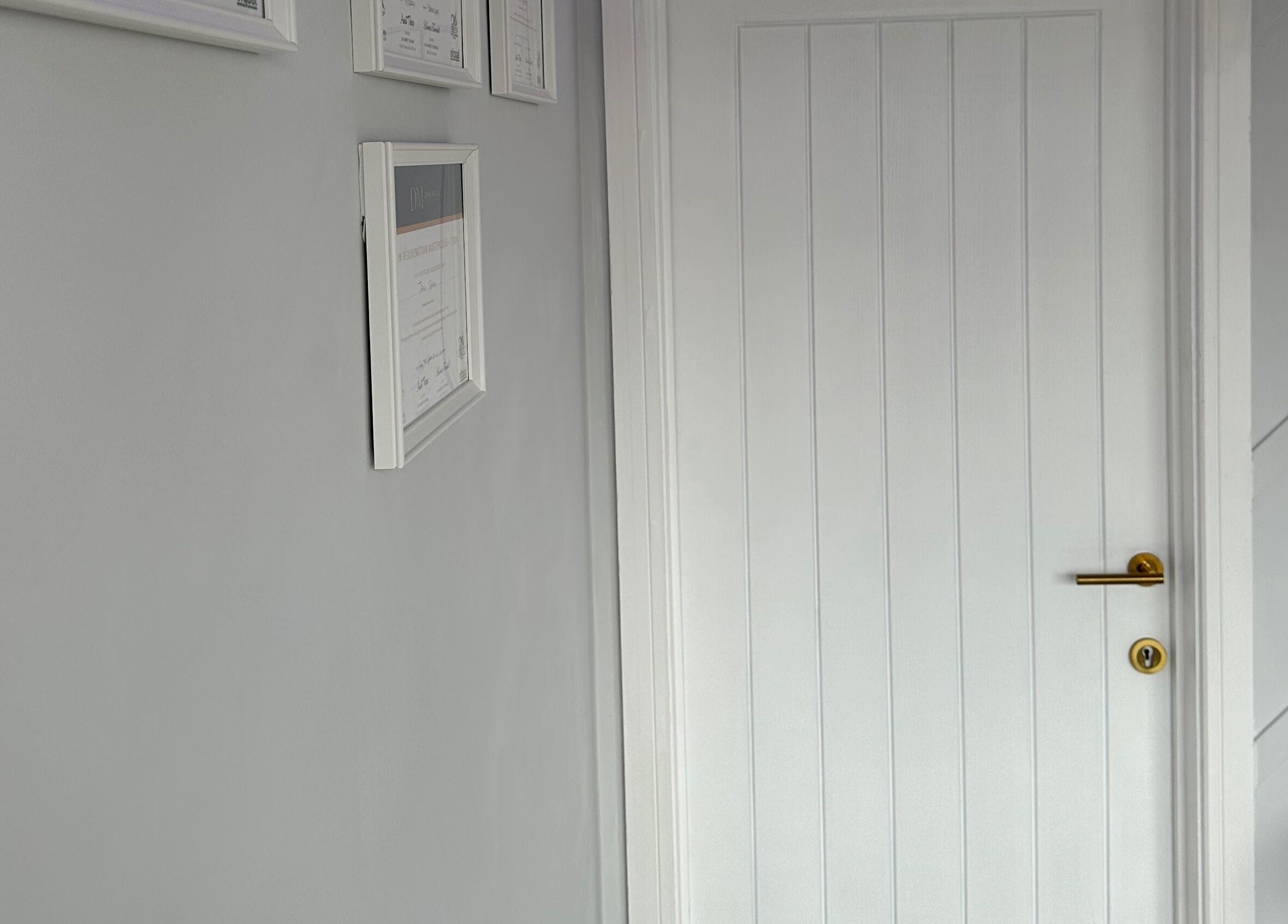 Framed certificates on a light grey wall by a door at Clear Touch Medical Aesthetics, Dudley, England, GB.