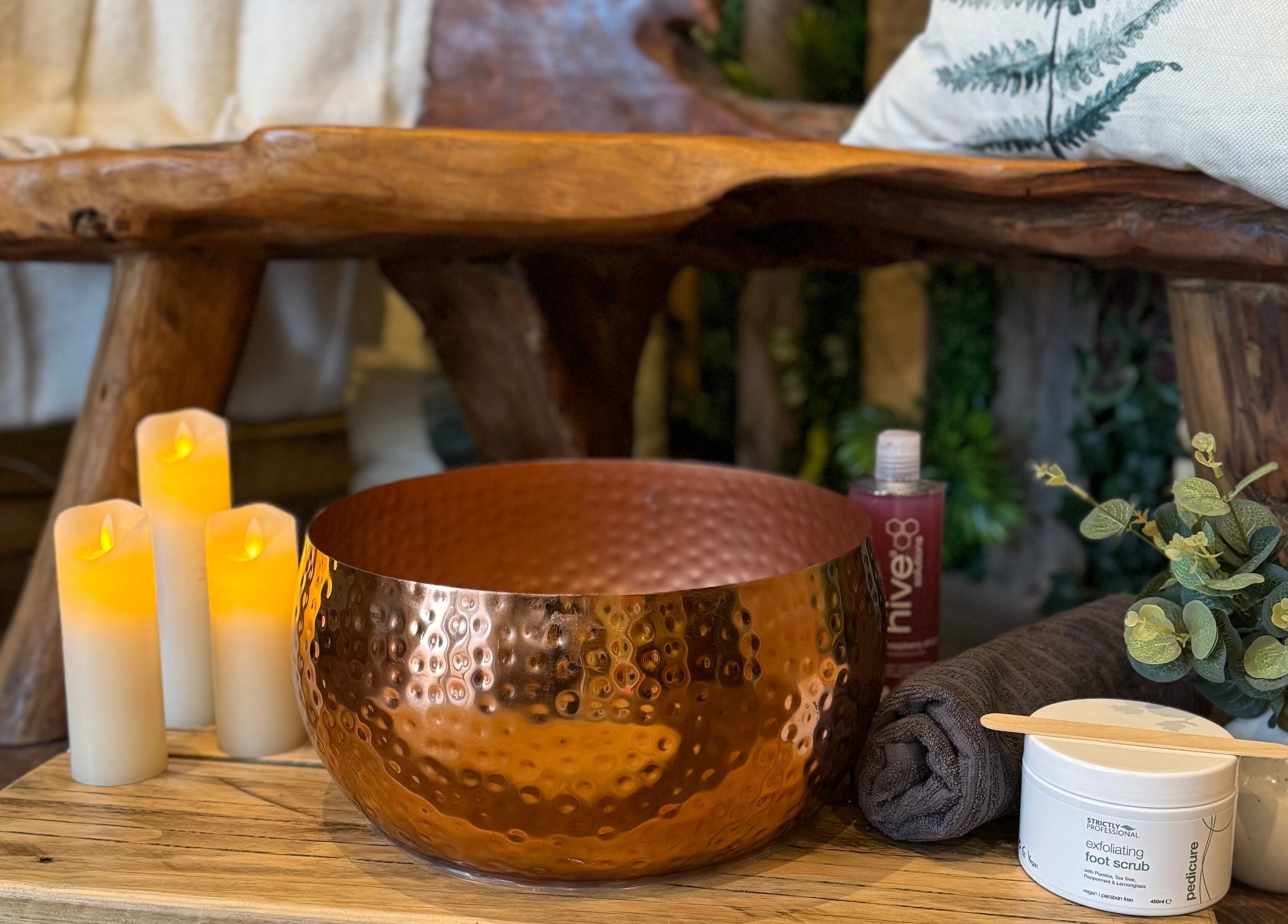 Beautiful spa setup at The Nurture Sanctuary, Broadwindsor, England, GB features candles, a copper bowl, and greenery.