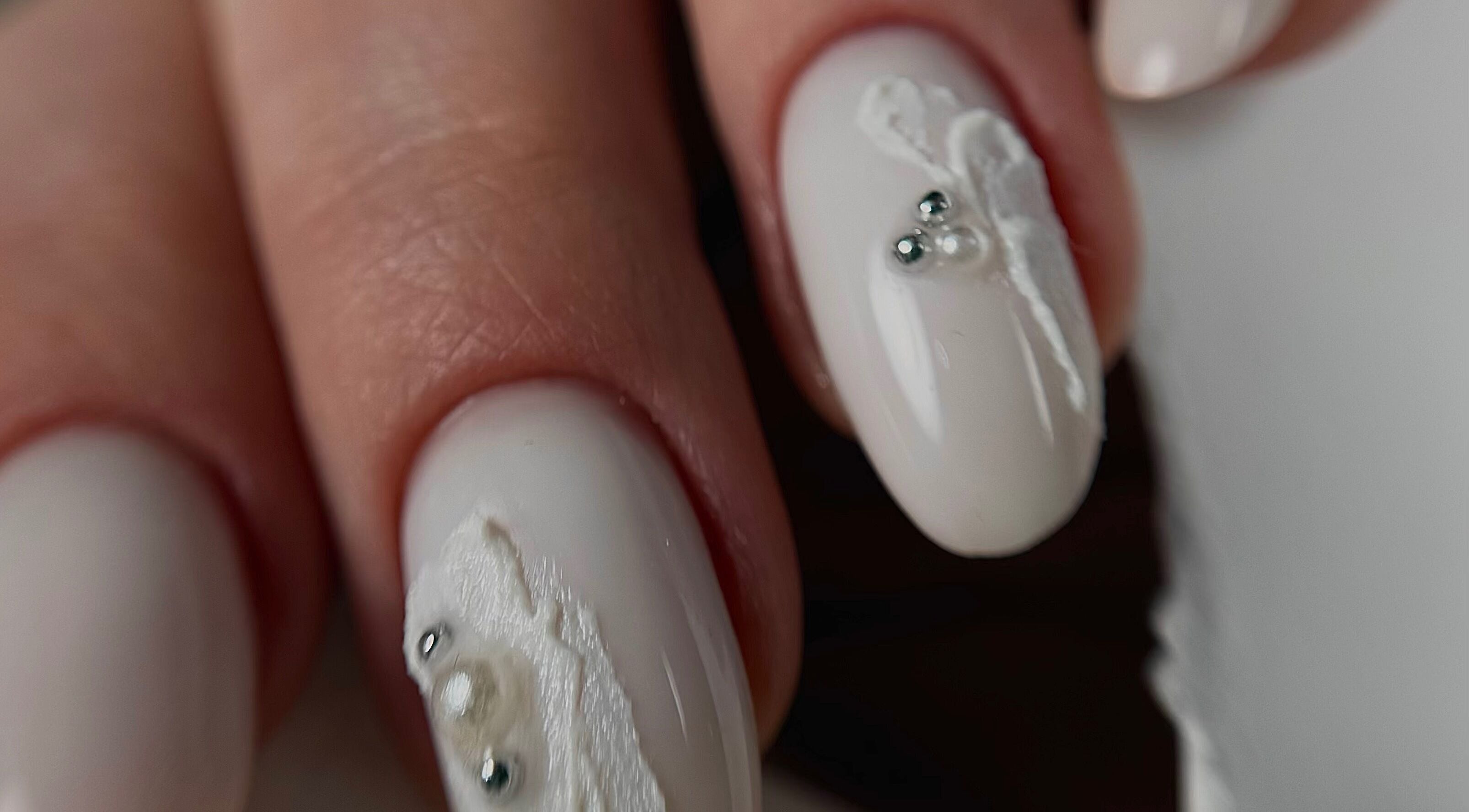 Close-up of white nail art at Yuliia Nails, Paris, Île-de-France, FR, showcasing intricate design.