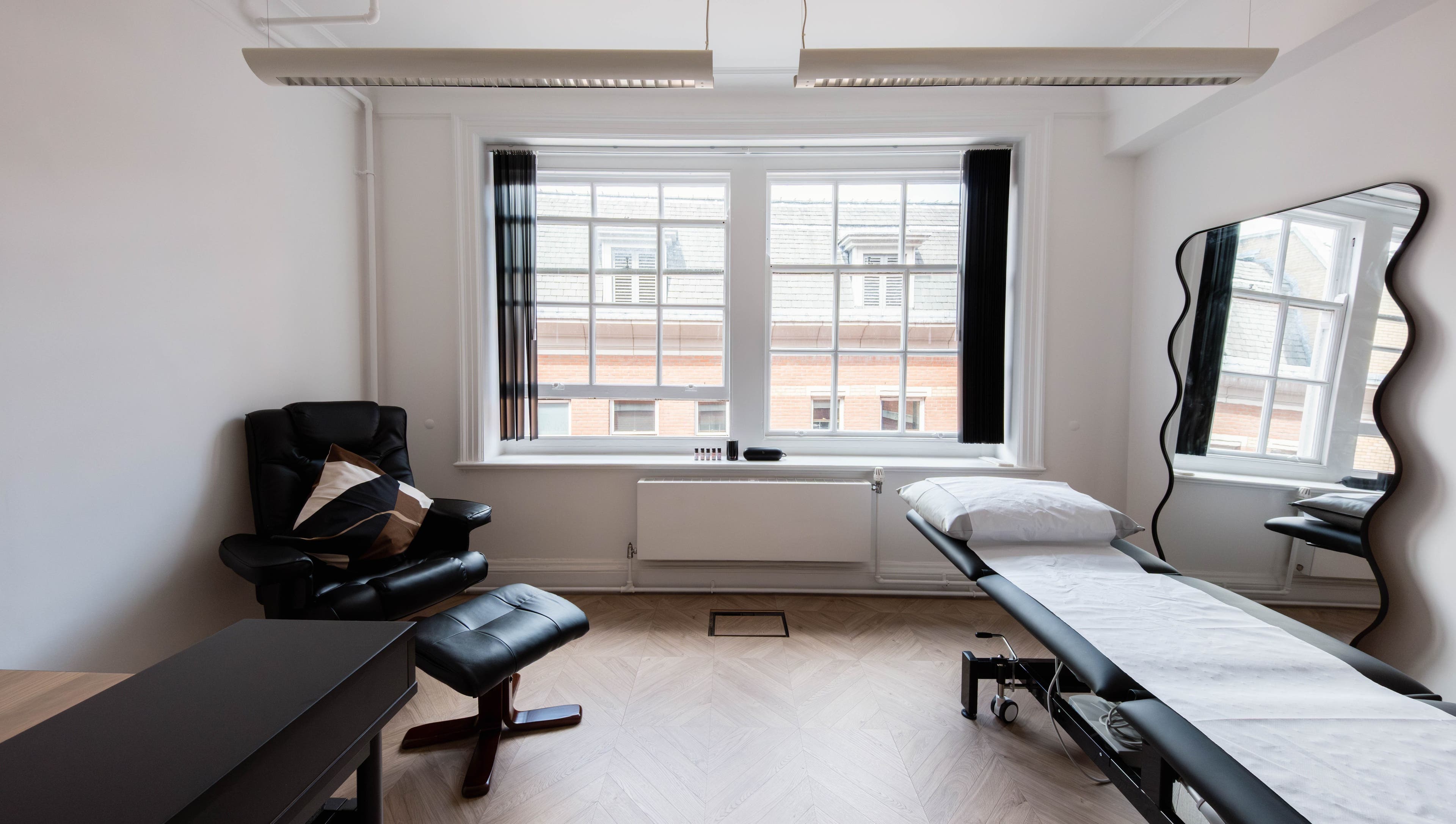 Relaxing treatment room at Soho Beauty & Aesthetics, London, England, GB, featuring a cozy chair and massage table.