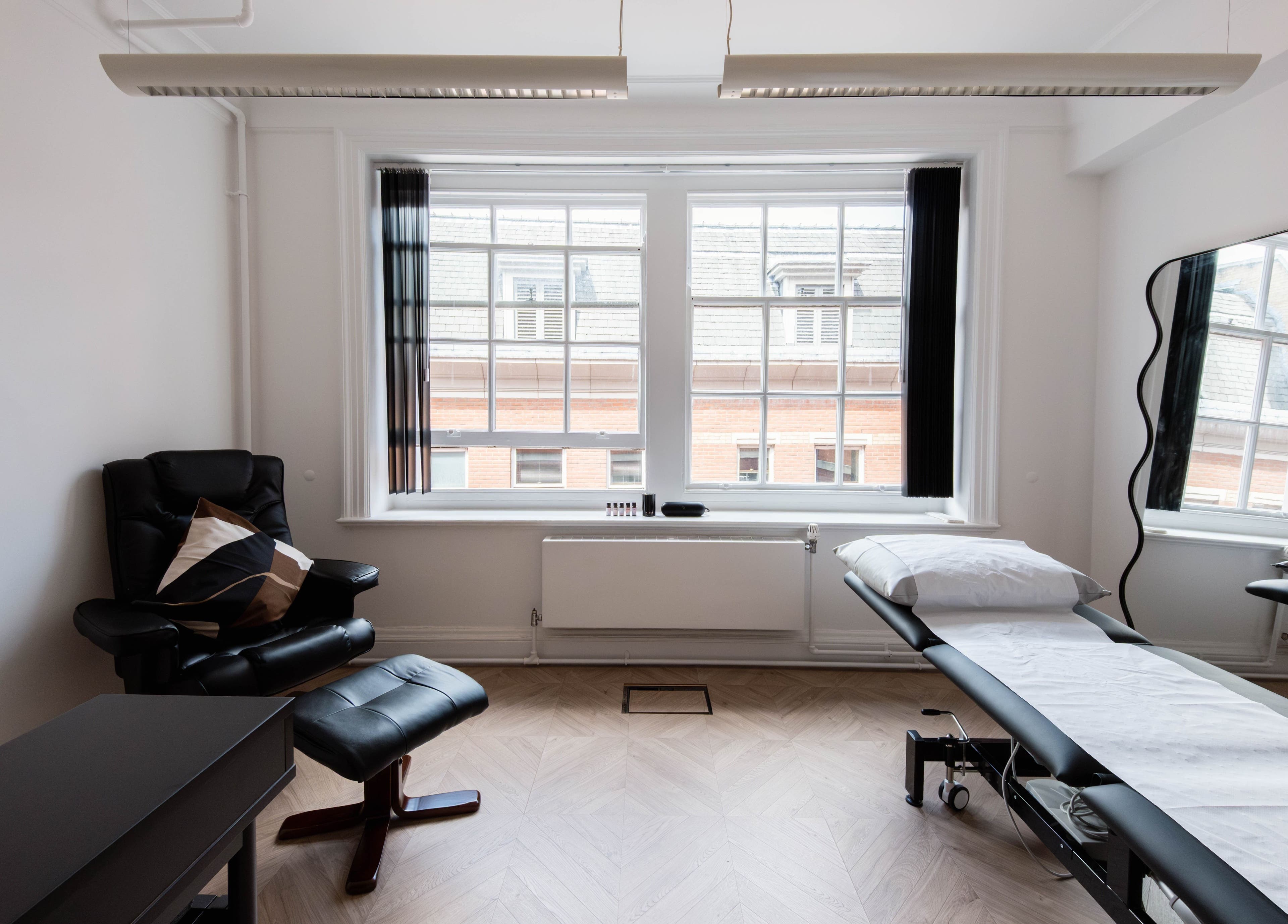 Relaxing treatment room at Soho Beauty & Aesthetics, London, England, GB, featuring a cozy chair and massage table.