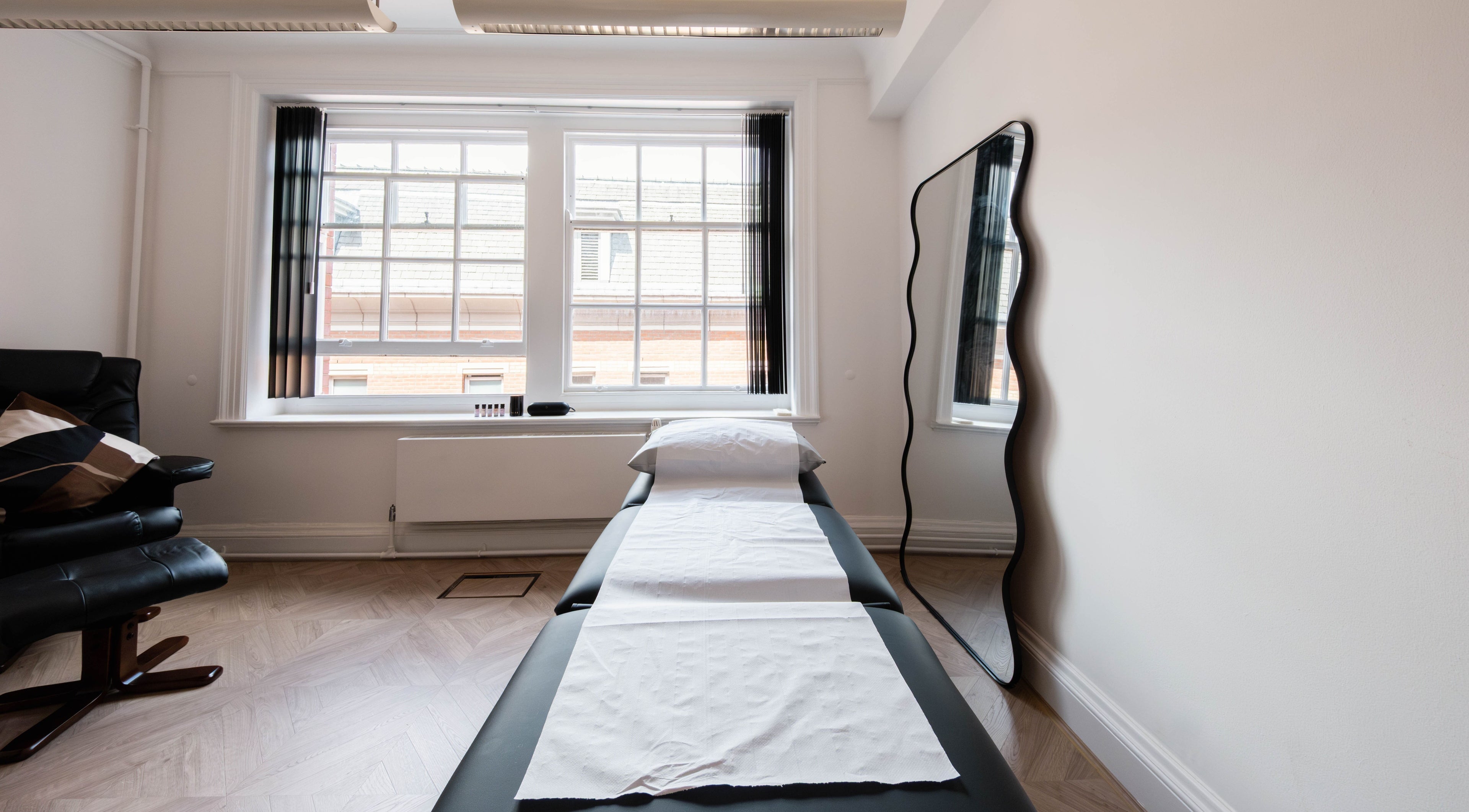 A tranquil treatment room at Soho Beauty & Aesthetics, London, England, GB, featuring a massage bed and natural light.