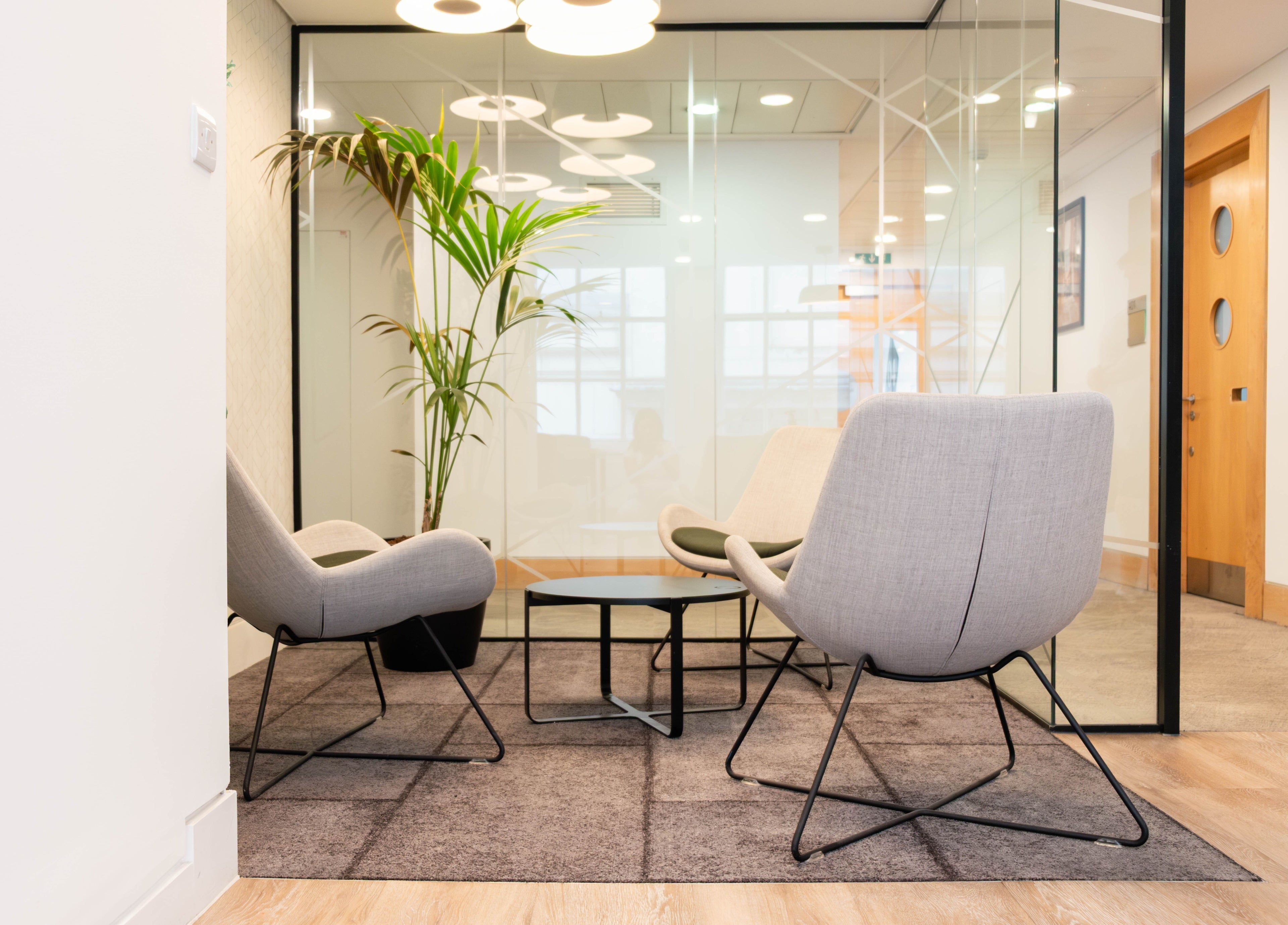 Modern seating area at Soho Beauty & Aesthetics, London, England, GB, with stylish chairs and potted plant.