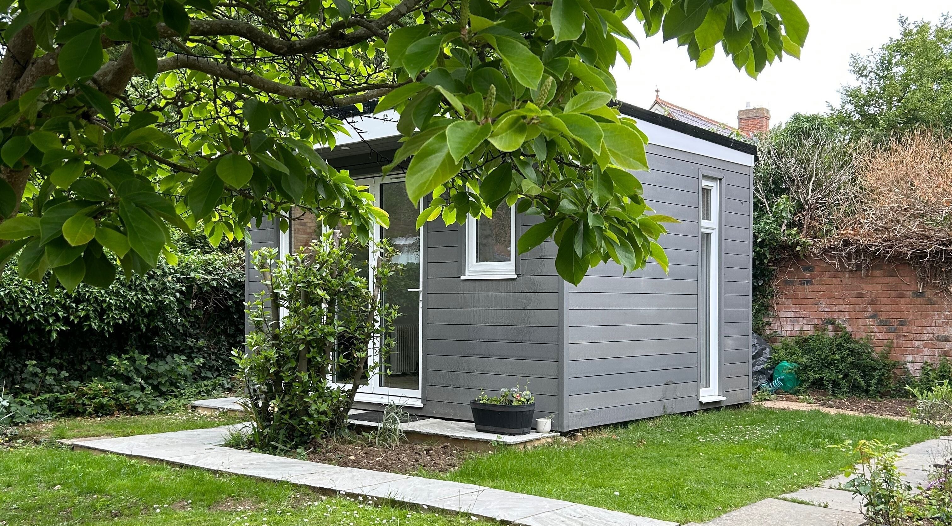 Peaceful garden cabin at DIVINEGLOWBYSOPHIE in Sandridge, England, GB, surrounded by lush greenery.
