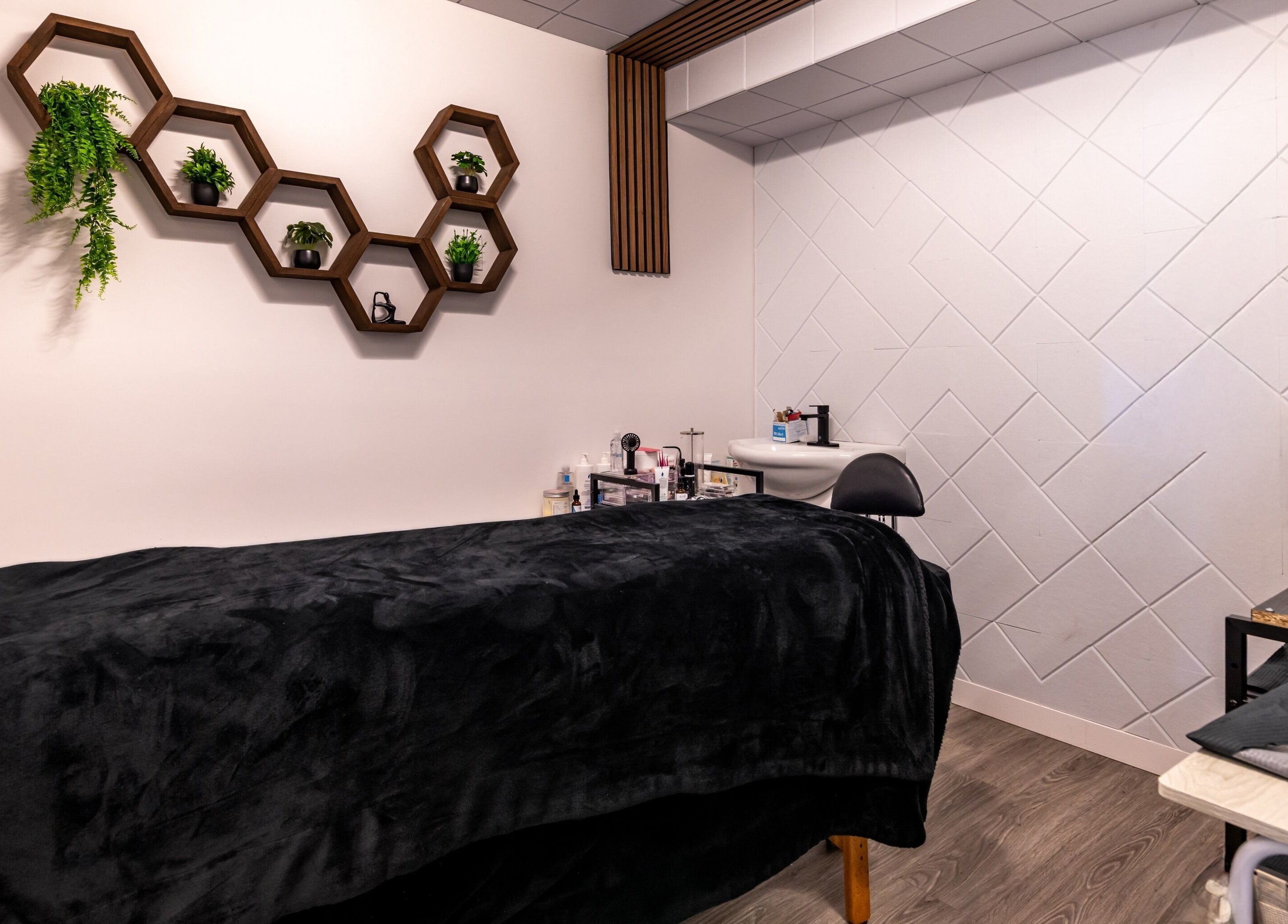 Salle de soin moderne à Spa Makia, L'île-perrot, Québec, CA avec étagères hexagonales et table de massage.