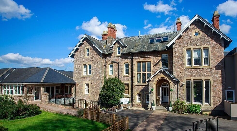 Exterior view of Flawless Clinic, a charming brick building in Wellington, England, GB under a bright blue sky.