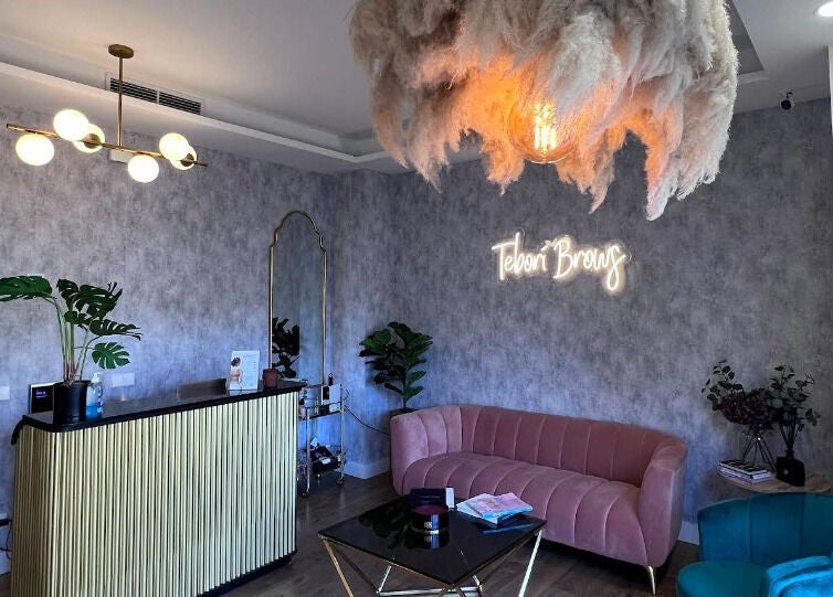 Recepción elegante en Teboribrows, Madrid, con sofá rosa y lámpara moderna.