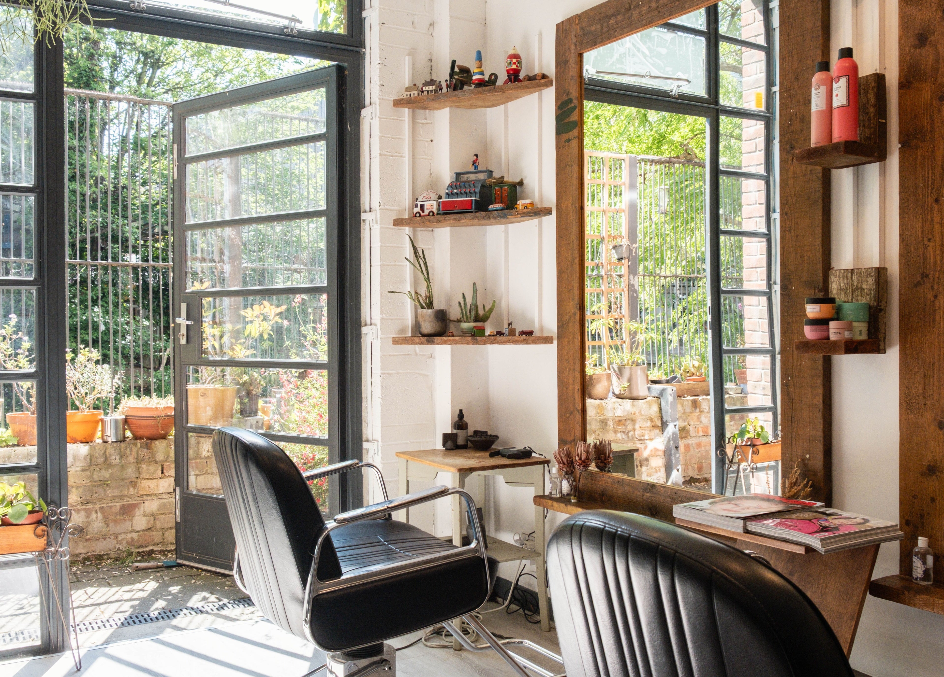 Bright salon interior at K Hair Studio, London, England, GB, with lush plants and sleek styling chair.