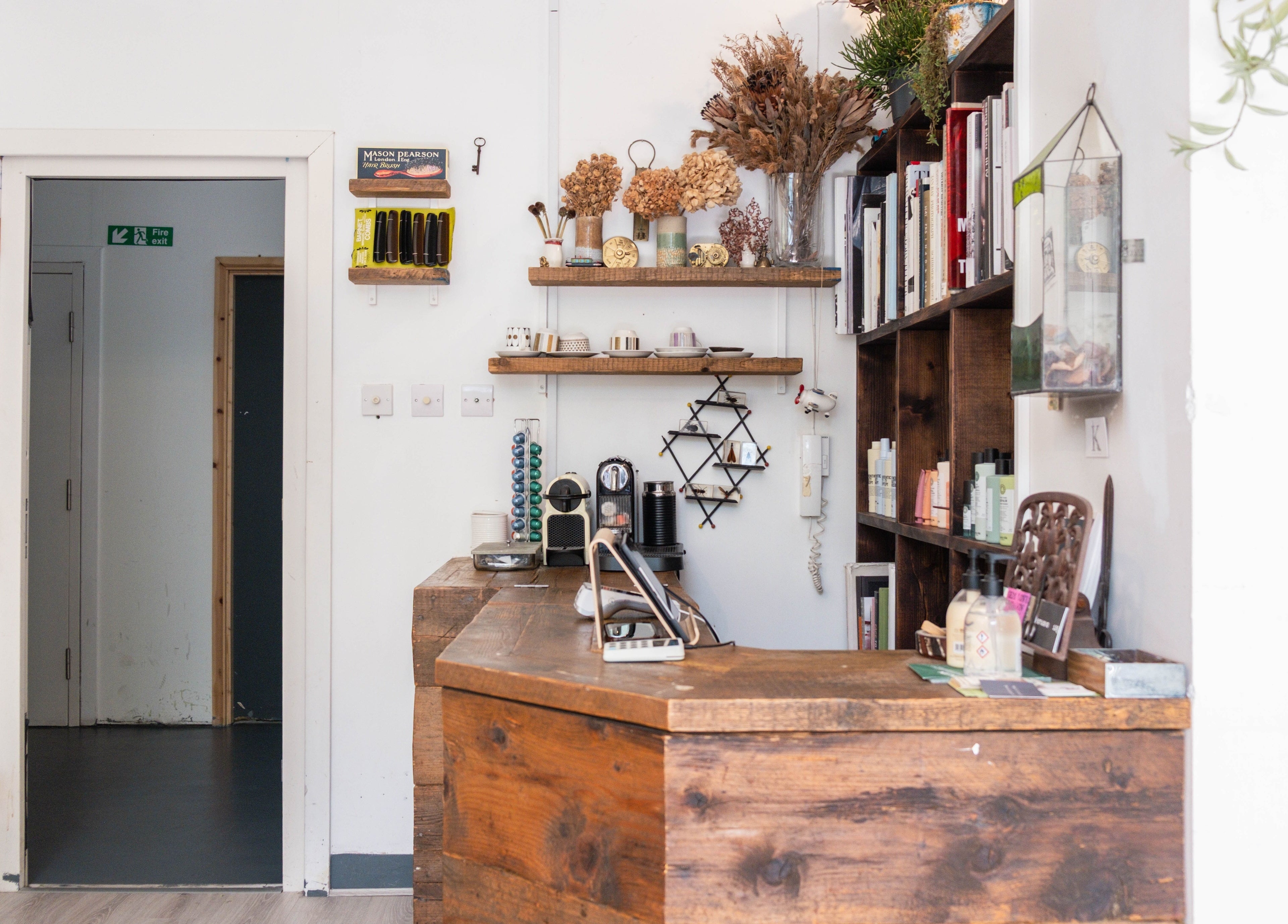 Charming reception at K Hair Studio, London, England, GB, showcasing rustic decor and product shelves.