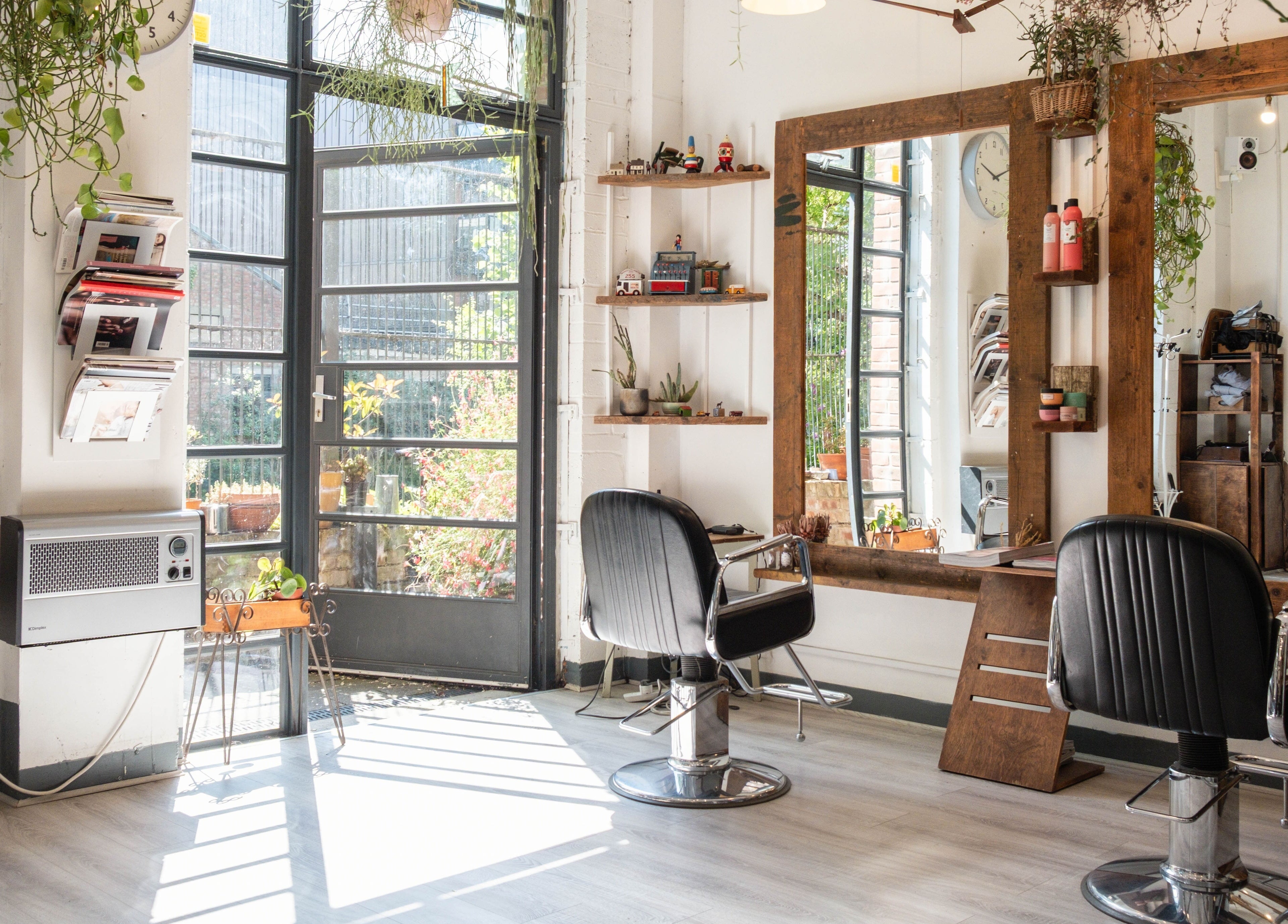 Bright and stylish interior of K Hair Studio in London, England, GB with modern salon chairs and mirrors.