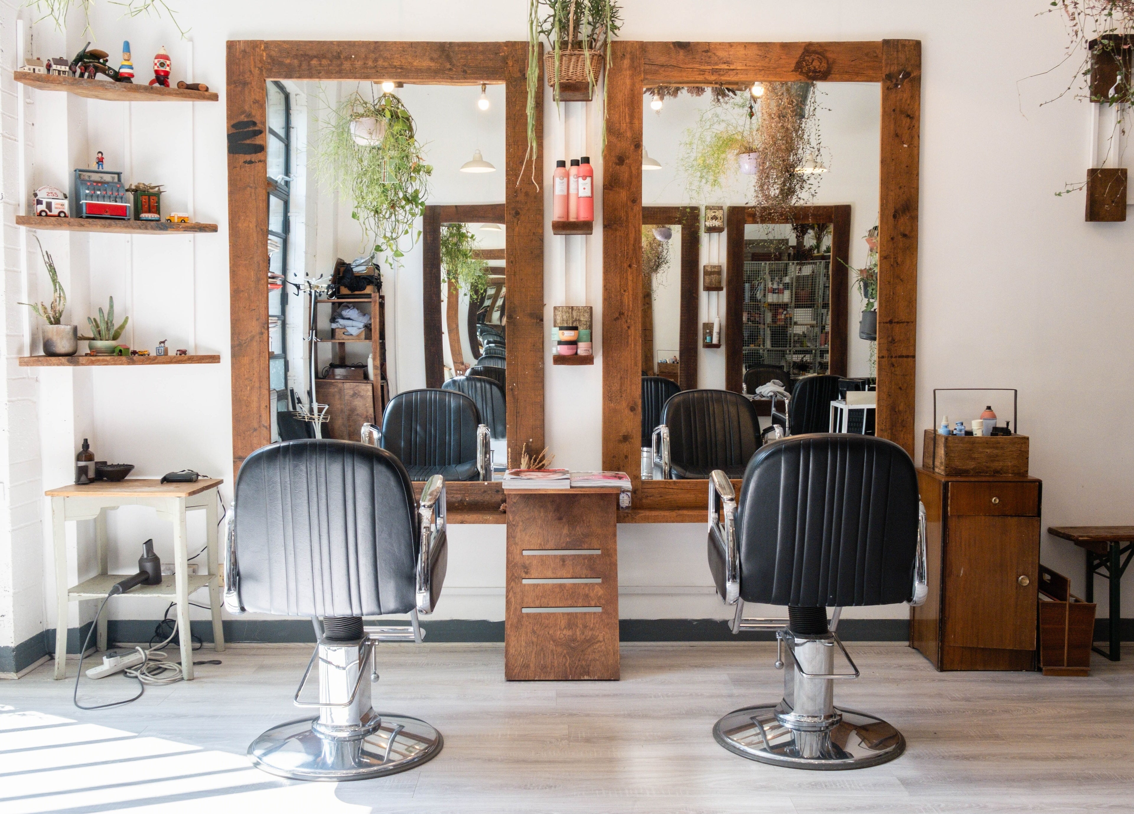 Interior of K Hair Studio in London, England, GB featuring stylish chairs and wooden mirrors.