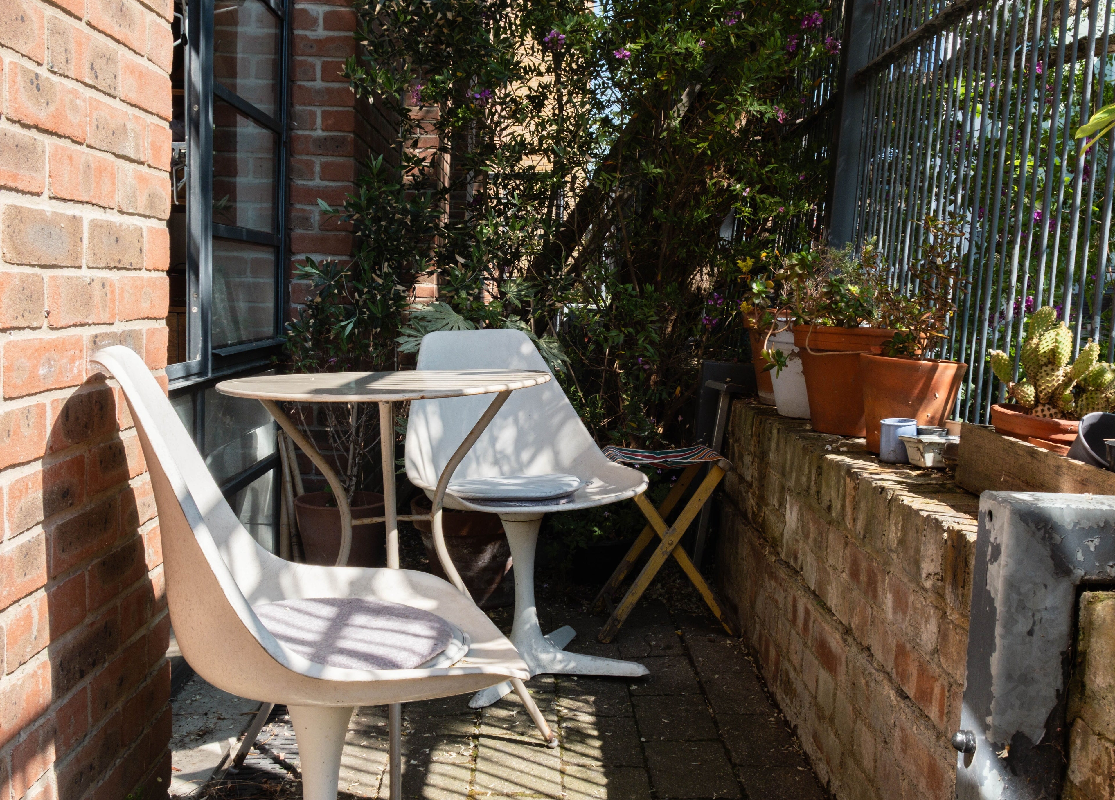 Serene outdoor seating area at K Hair Studio, London, England, GB, surrounded by lush greenery and potted plants.