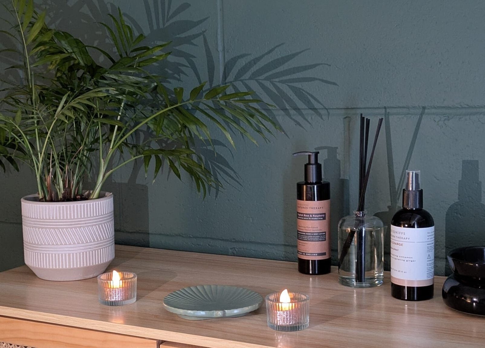 Calming spa setup at New Leaf Massage, Brandon, England, GB with candles, plants, and aromatherapy bottles.