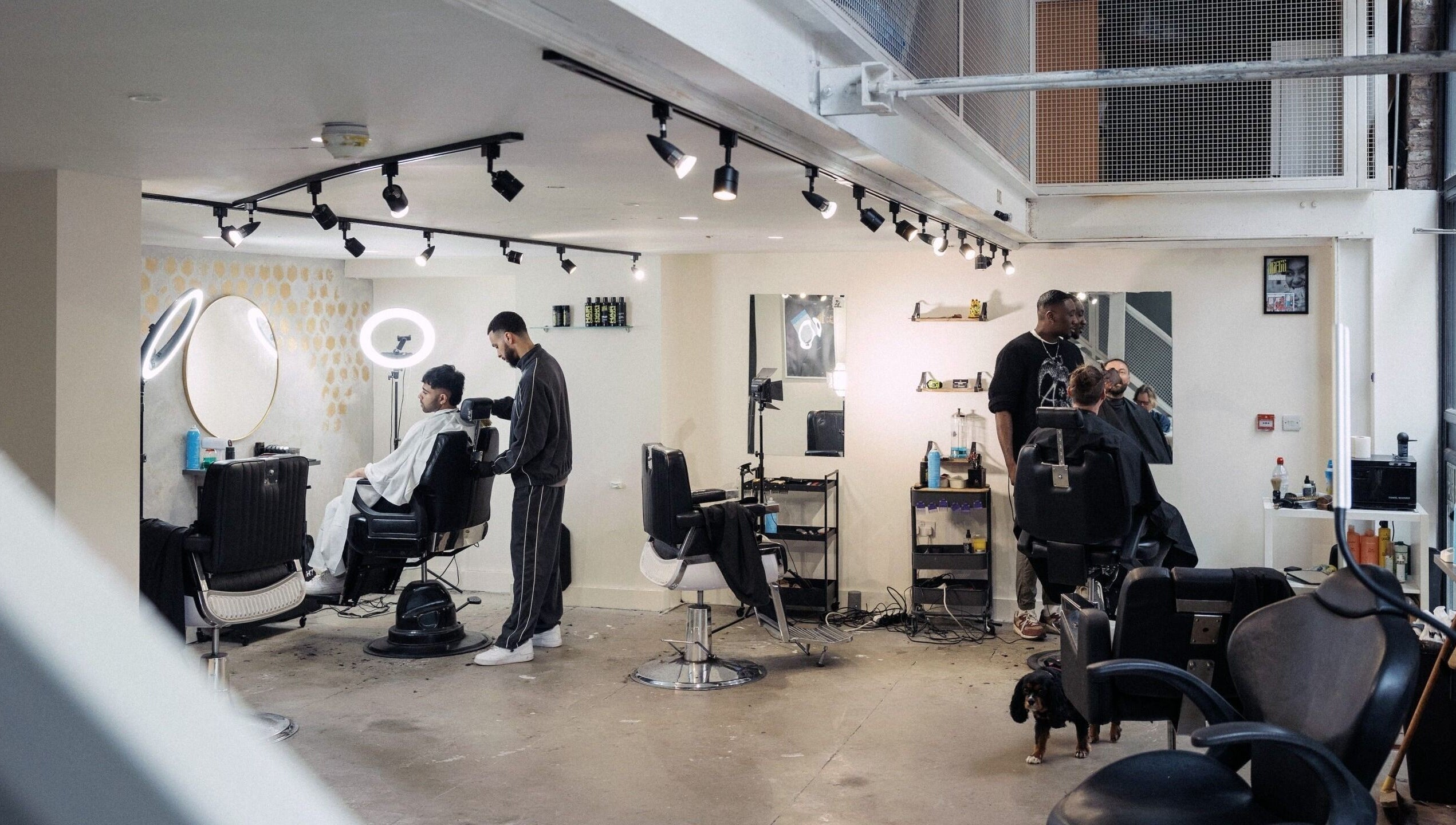 Modern interior of Jefe Barbers in Stockport, England, GB with stylists at work and clients in chairs.
