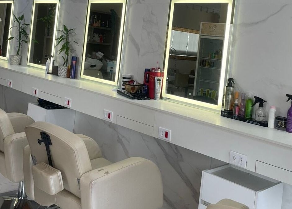 Interior moderno do Renata Magalhães studio em São Paulo, BR, com espelhos iluminados e cadeiras de salão.