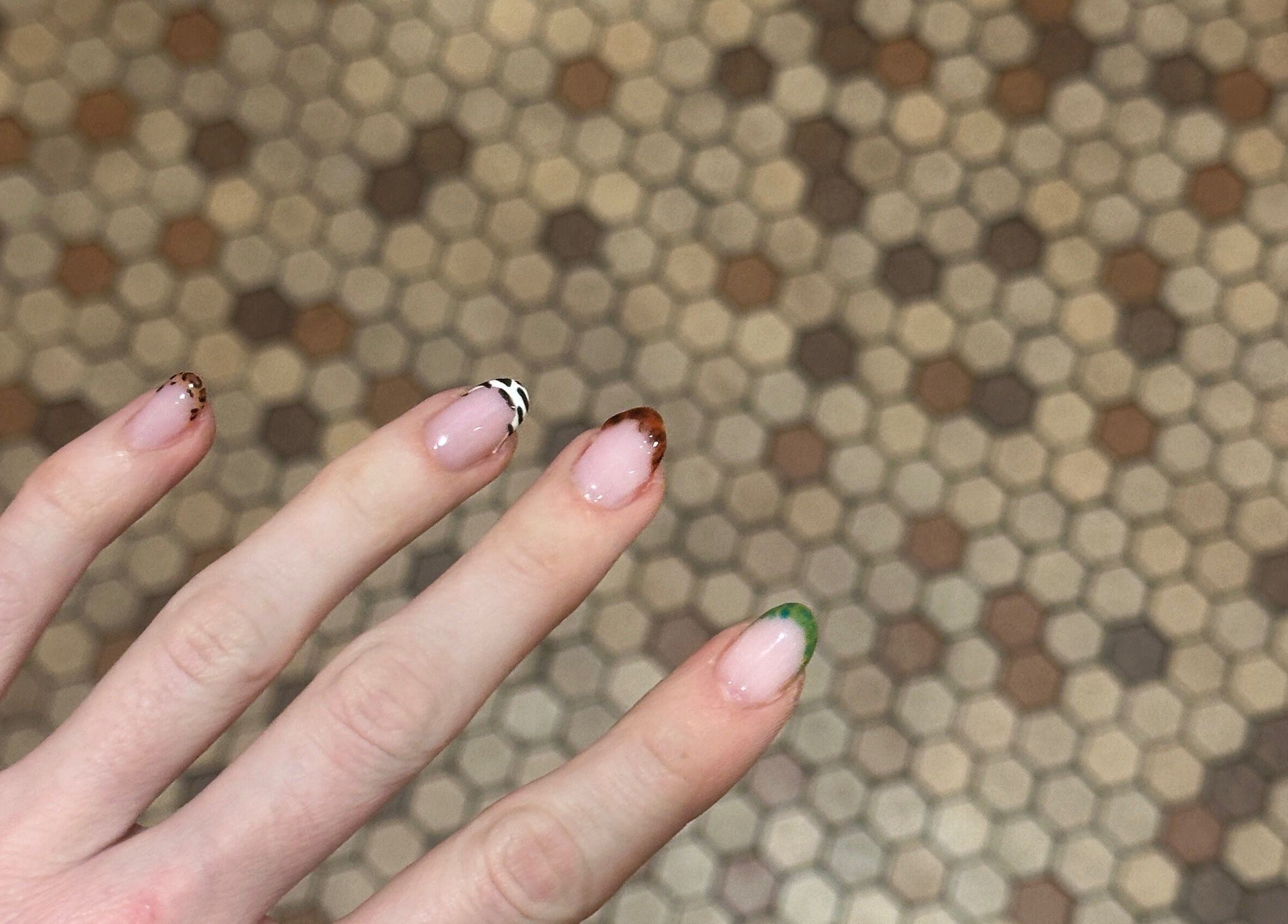 Stylish nail art at Butter Nails, Hamilton, Waikato, NZ, showcasing trendy designs on a hexagonal tile background.