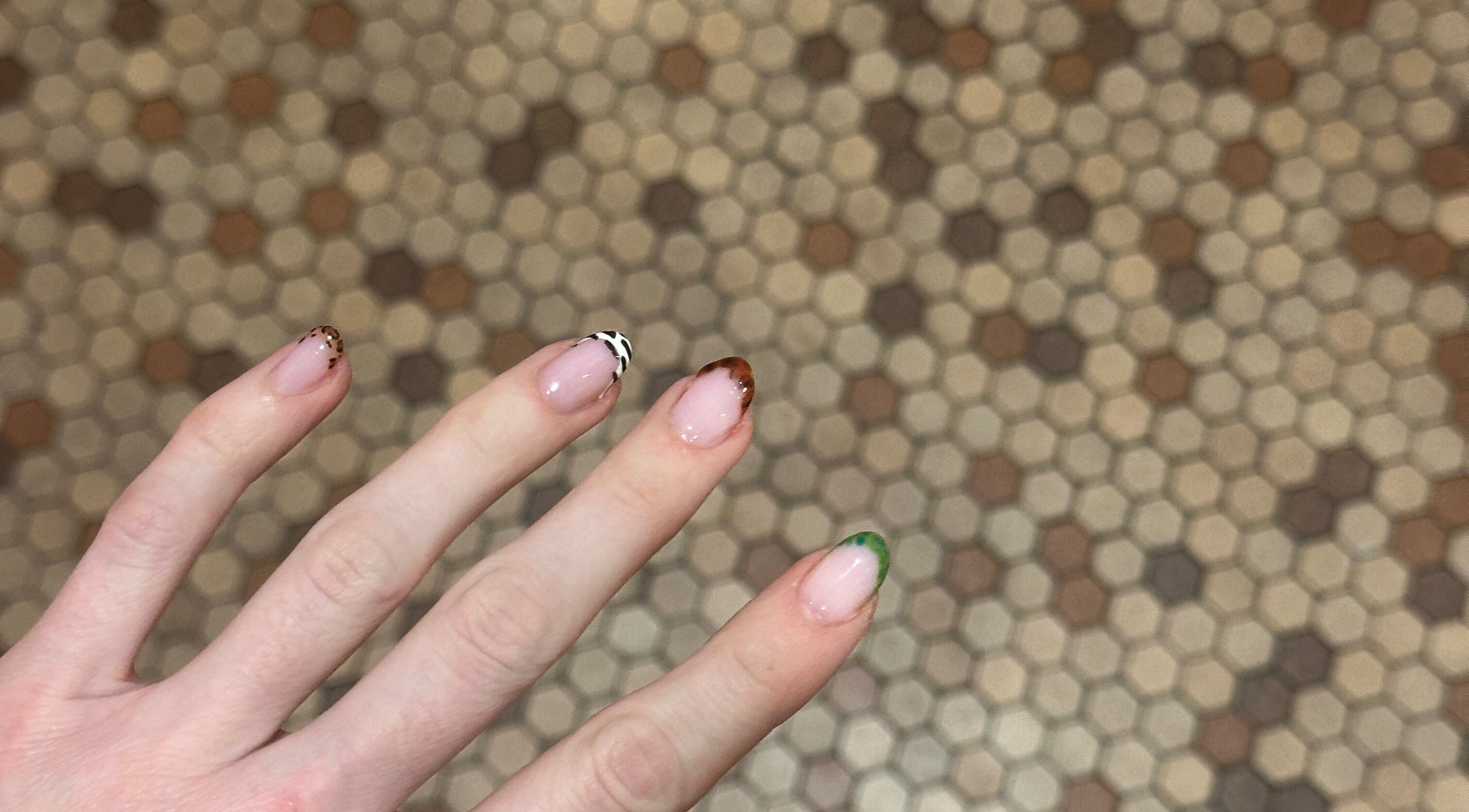 Stylish nail art at Butter Nails, Hamilton, Waikato, NZ, showcasing trendy designs on a hexagonal tile background.
