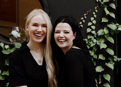 Two women smiling joyfully at House of Kieulder, Pretoria, Gauteng, ZA, surrounded by lush greenery.