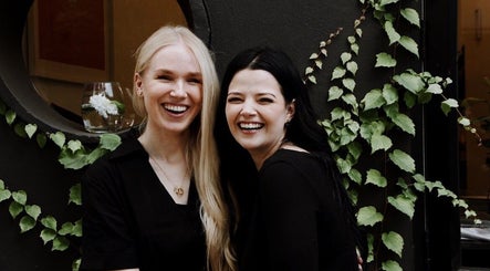 Two women smiling joyfully at House of Kieulder, Pretoria, Gauteng, ZA, surrounded by lush greenery.