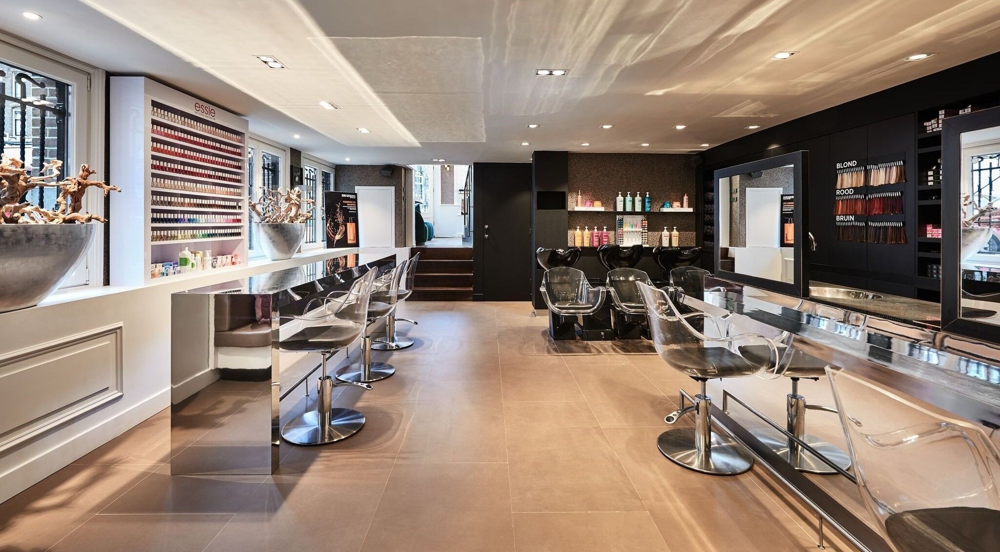 Moderne saloninterieur bij PIERÔT AMSTERDAM in Amsterdam, Noord-Holland, NL met strakke stoelen en kleurrijke producten.