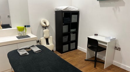 Cozy massage room at AR Sports Massage, London, England, GB, featuring a black massage table and modern decor.