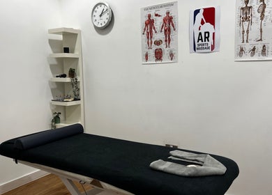 Therapy room at AR Sports Massage in London, England, GB with massage table and anatomical charts.