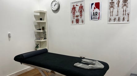 Therapy room at AR Sports Massage in London, England, GB with massage table and anatomical charts.