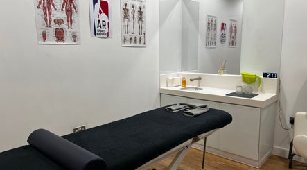 AR Sports Massage treatment room with a massage bed and anatomical charts, London, England, GB.