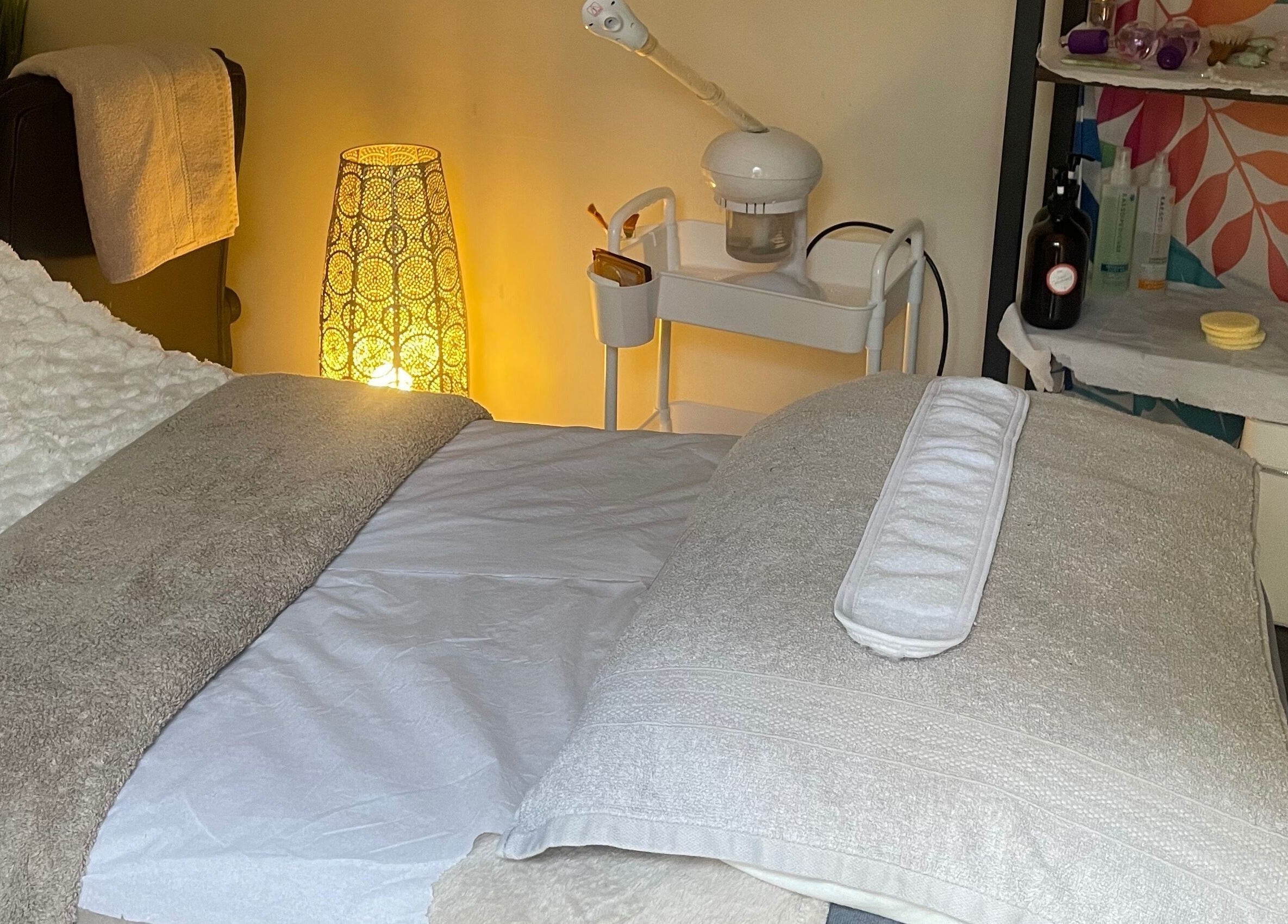 Cozy spa bed at Lillie Rose Beauty, Worthing, England, GB with soft lighting and skincare products.