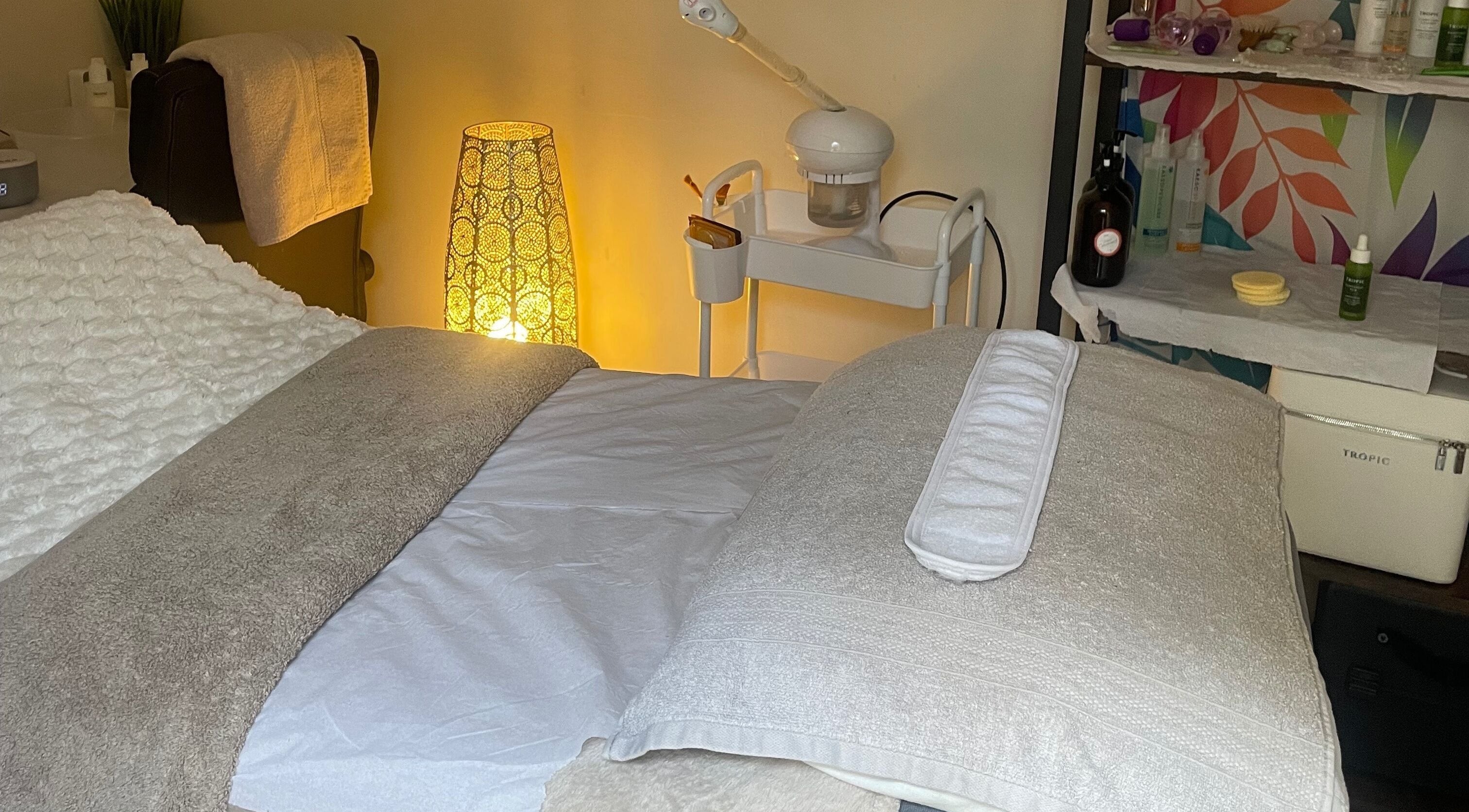 Cozy spa bed at Lillie Rose Beauty, Worthing, England, GB with soft lighting and skincare products.