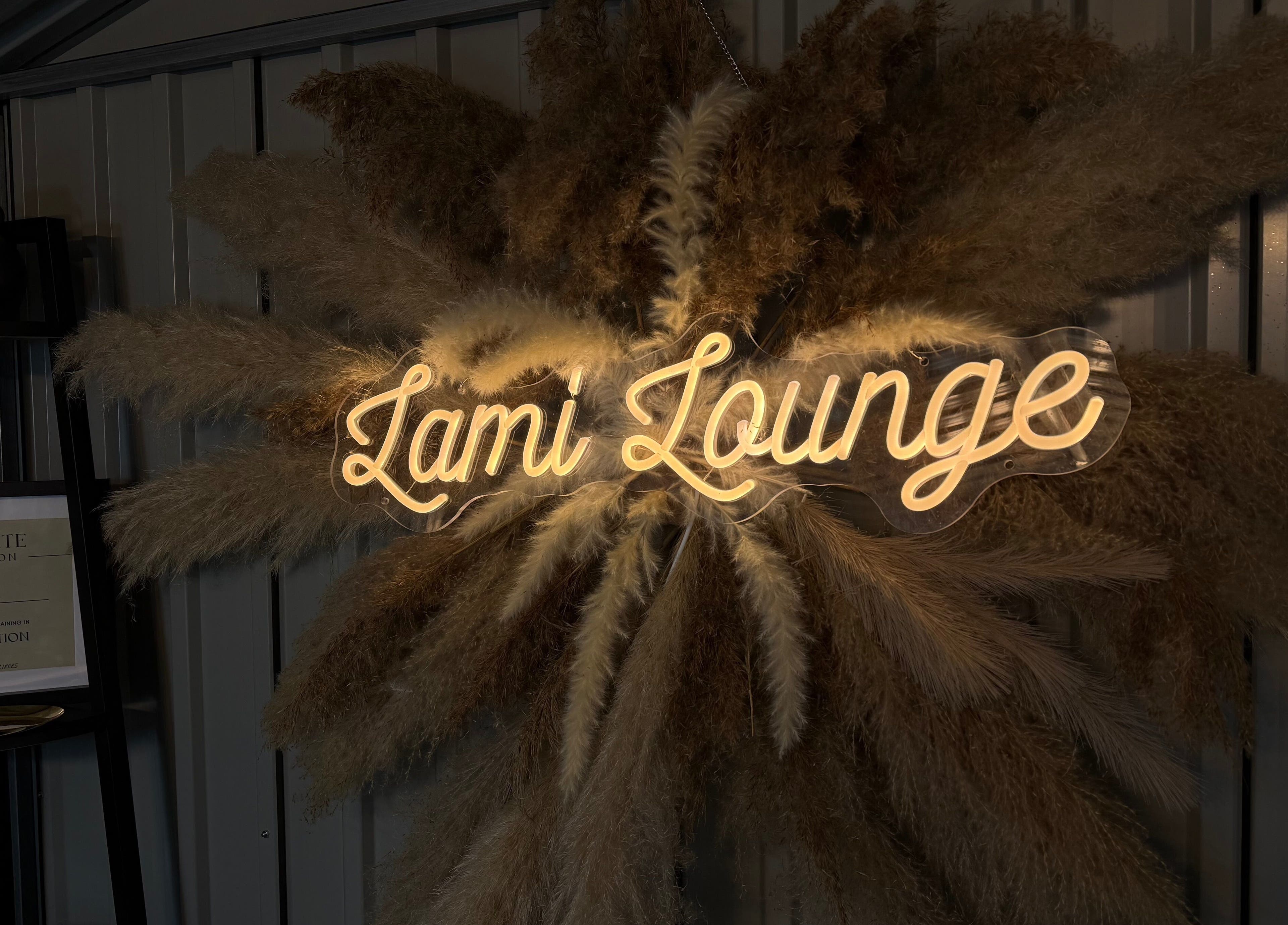 Illuminated 'Lami Lounge UK' sign with pampas grass in Spalding, England, GB.