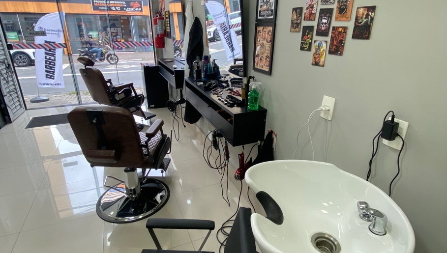 Interior da Barbearia Dom André em São Paulo, BR, mostrando cadeiras de barbeiro e estação de trabalho.