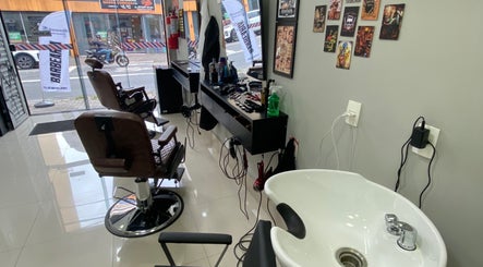 Interior da Barbearia Dom André em São Paulo, BR, mostrando cadeiras de barbeiro e estação de trabalho.