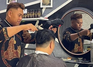 Barber styling a customer's hair at Borneo Barbershop Sabindo, Penampang, Sabah, MY.