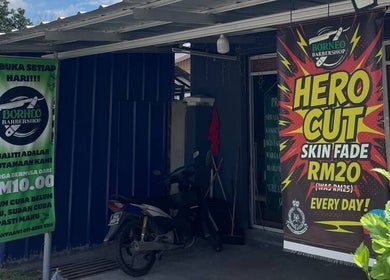 Borneo Barbershop Sabindo exterior in Penampang, Sabah, MY with colorful Hero Cut signs.