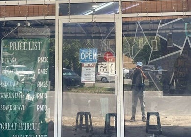 Entrance of Borneo Barbershop Sabindo in Penampang, Sabah, MY, showing price list and open sign.