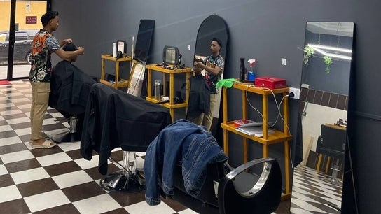 Inside Borneo Barbershop Putatan, Sabah, MY with barber attending to a customer on a stylish checkered floor.