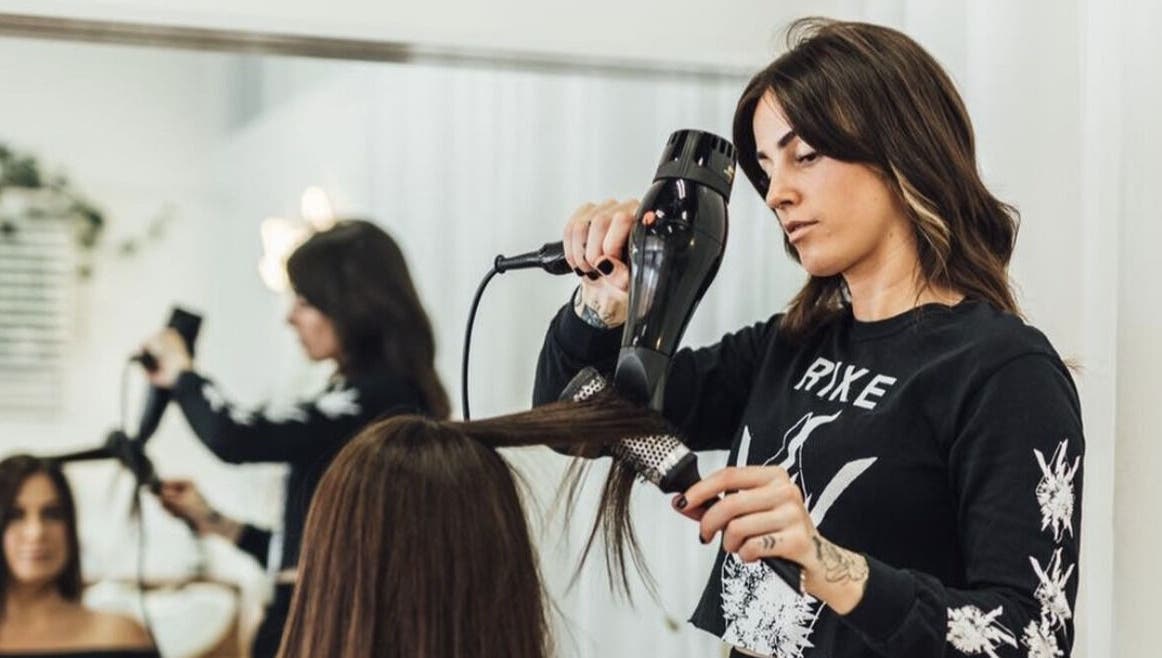 Stylist blow-drying hair at Growth Salon in Fadden, ACT, AU, showcasing professional hair services.
