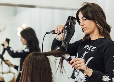 Stylist blow-drying hair at Growth Salon in Fadden, ACT, AU, showcasing professional hair services.