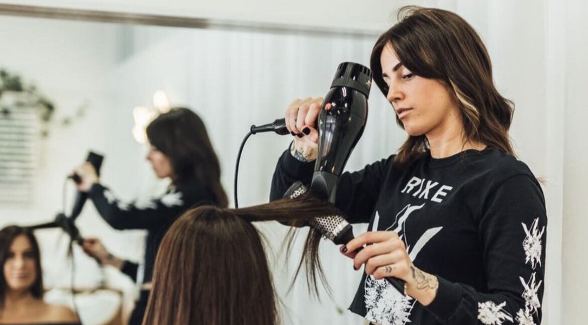 Stylist blow-drying hair at Growth Salon in Fadden, ACT, AU, showcasing professional hair services.