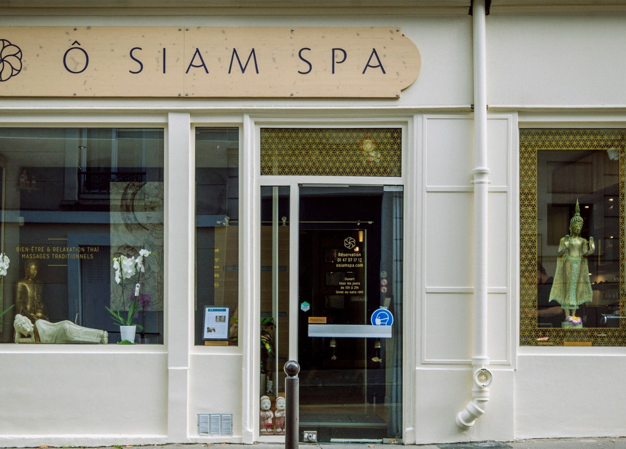 Entrée de Ô Siam Spa Paris 5 à Paris, Île-de-France, FR, avec statue et orchidées en vitrine.