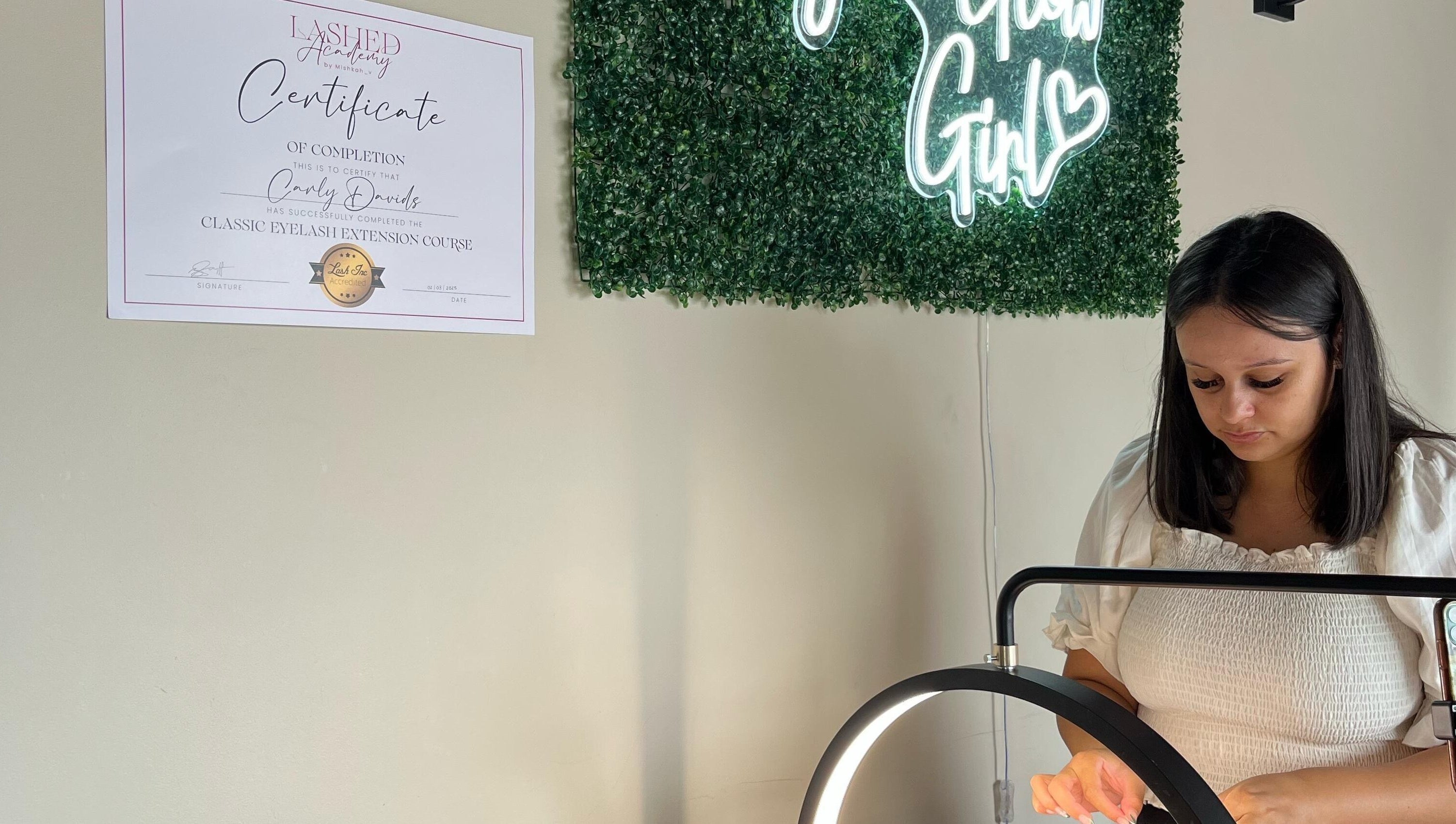 Lash artist at Lashed by CD in Cape Town, Western Cape, ZA, showcasing skills with a glowing sign backdrop.