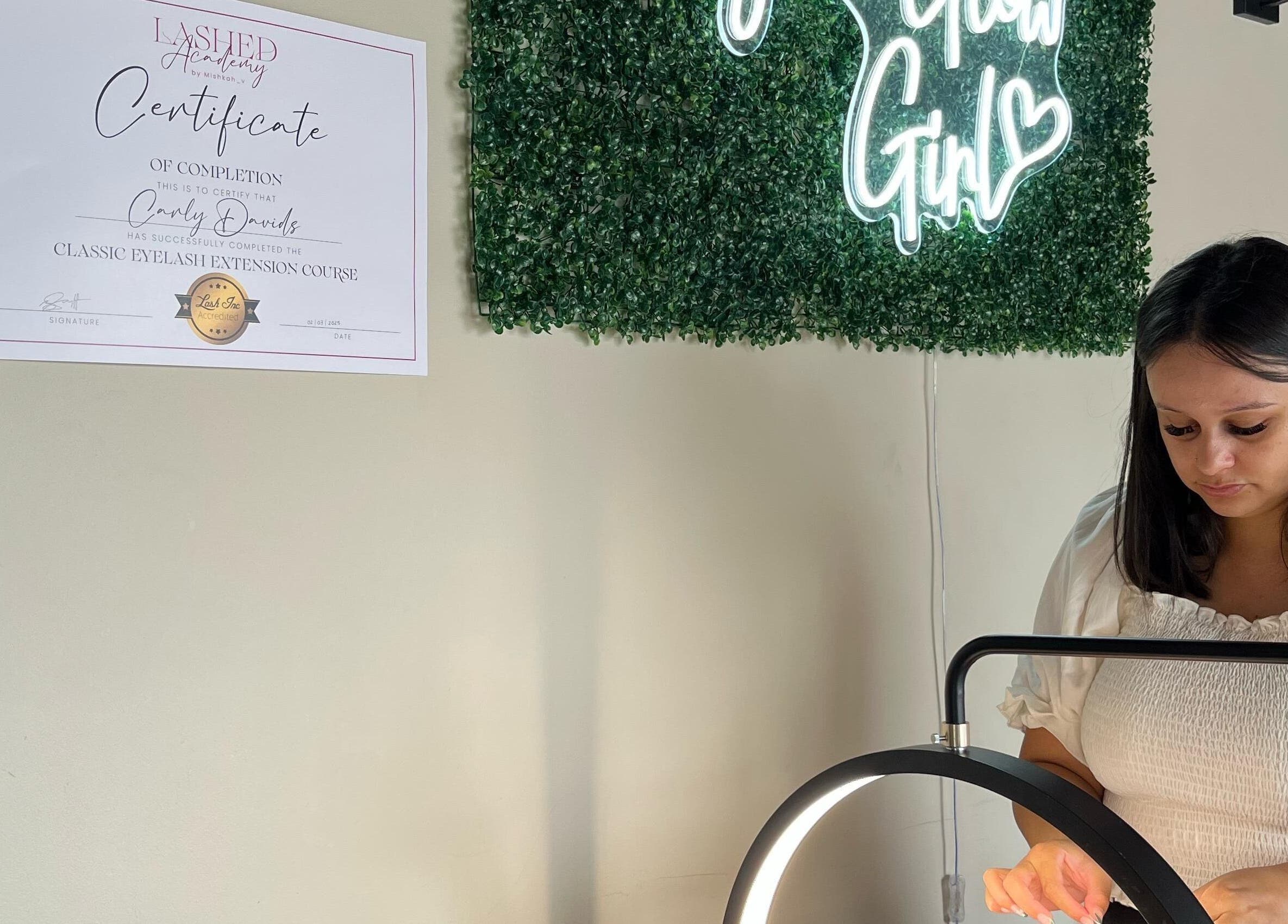 Lash artist at Lashed by CD in Cape Town, Western Cape, ZA, showcasing skills with a glowing sign backdrop.