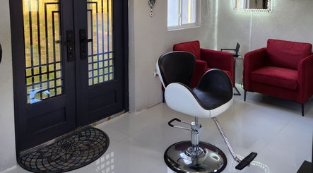 Modern salon seating area at B Fierce Salon Barbados, Deanes, Saint James, BB, with sleek chair and red armchairs.